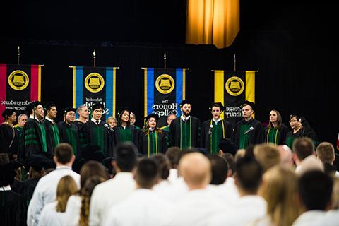 在毕业典礼上，俄亥俄州立大学合唱合唱团2018届毕业生在彩旗前的舞台上唱歌